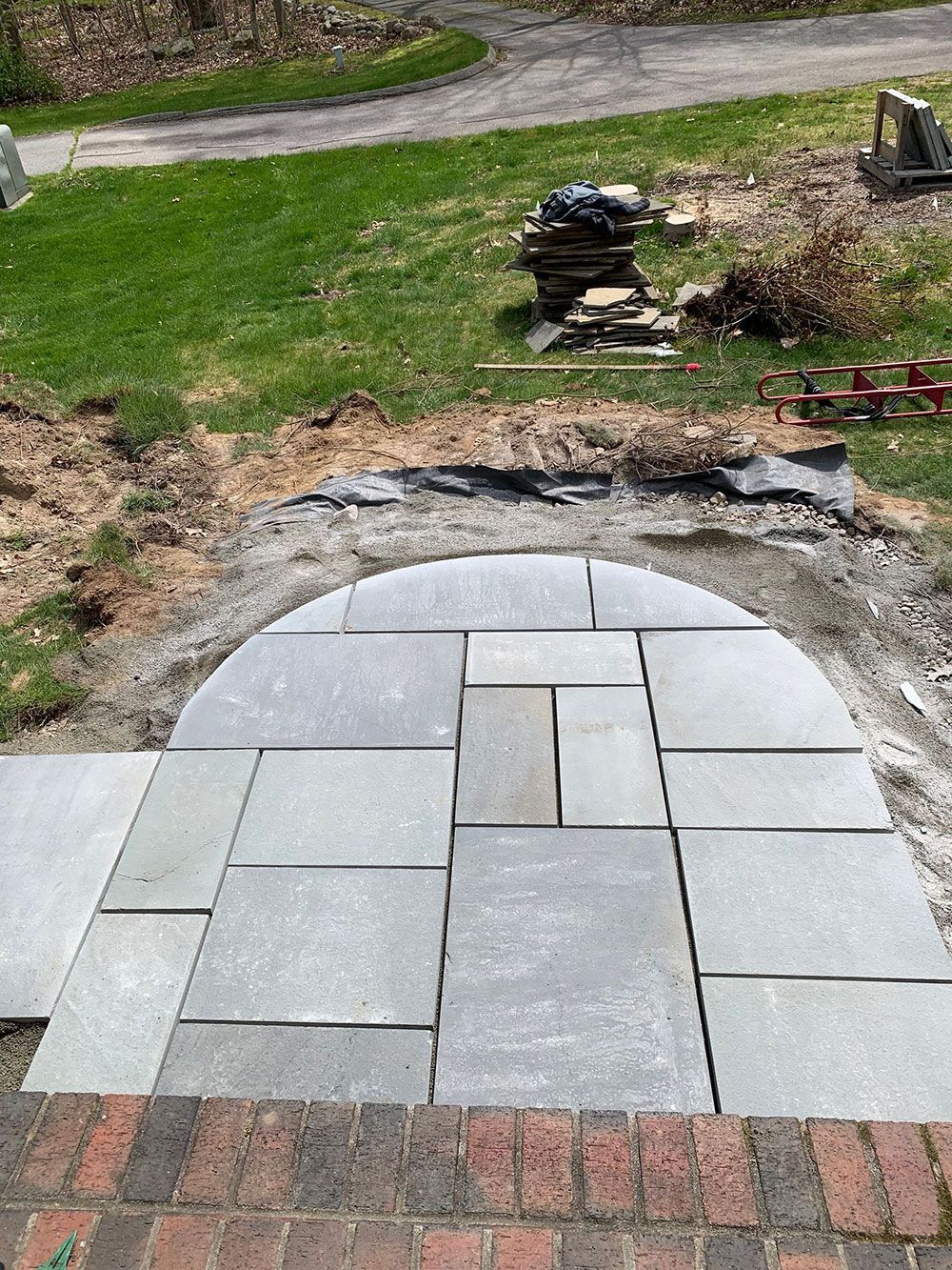 A stone walkway is being built in a backyard