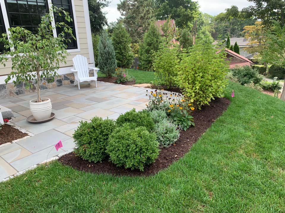a patio with a chair and plants in front of a house
