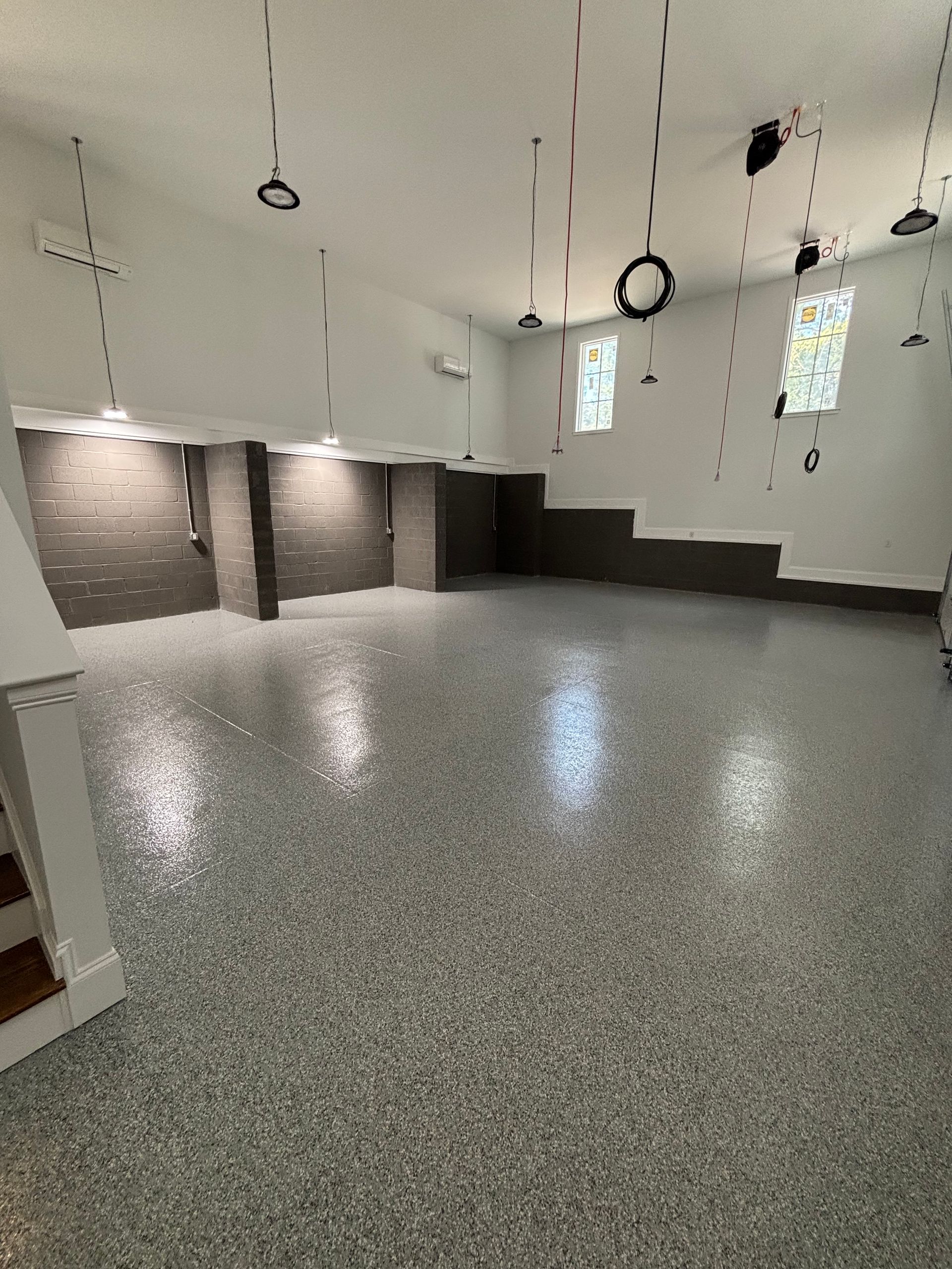 Spacious room with speckled floor, steps, dark accent walls, and hanging lights.