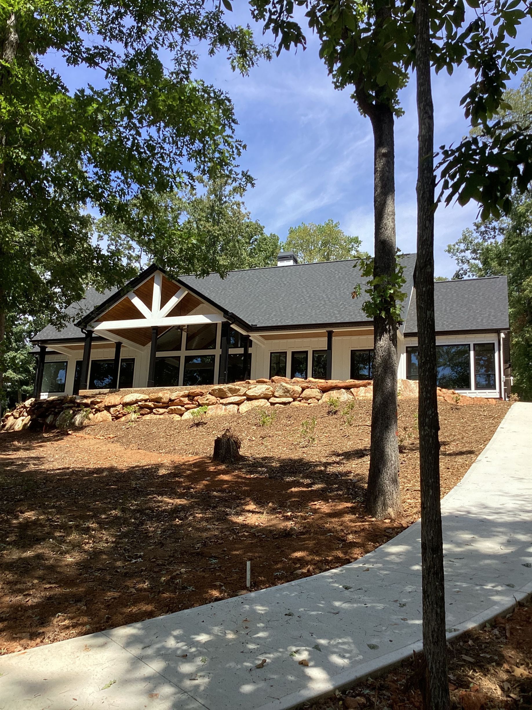 A large house is surrounded by trees and a concrete walkway.
