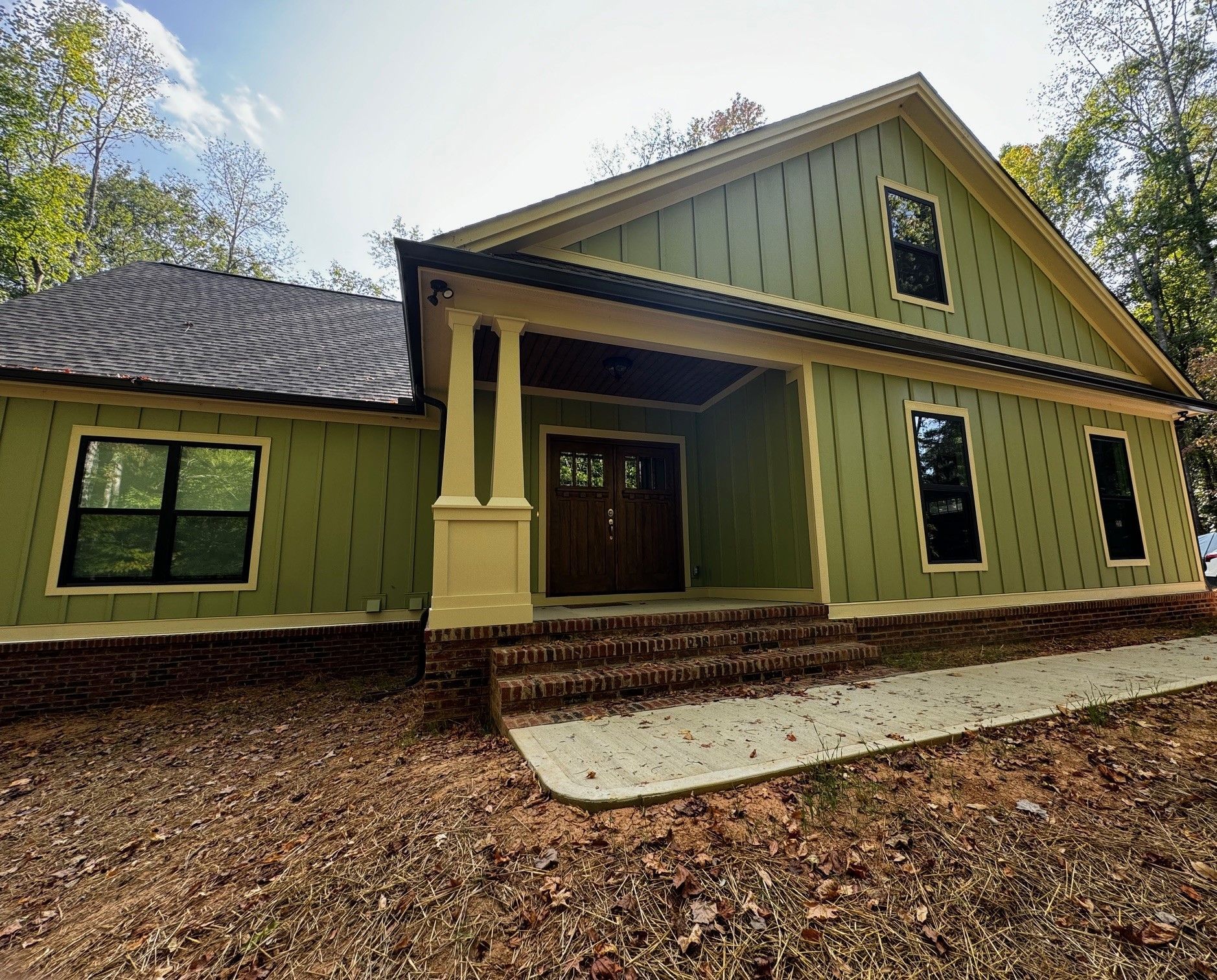 A green and yellow house with a porch and stairs.