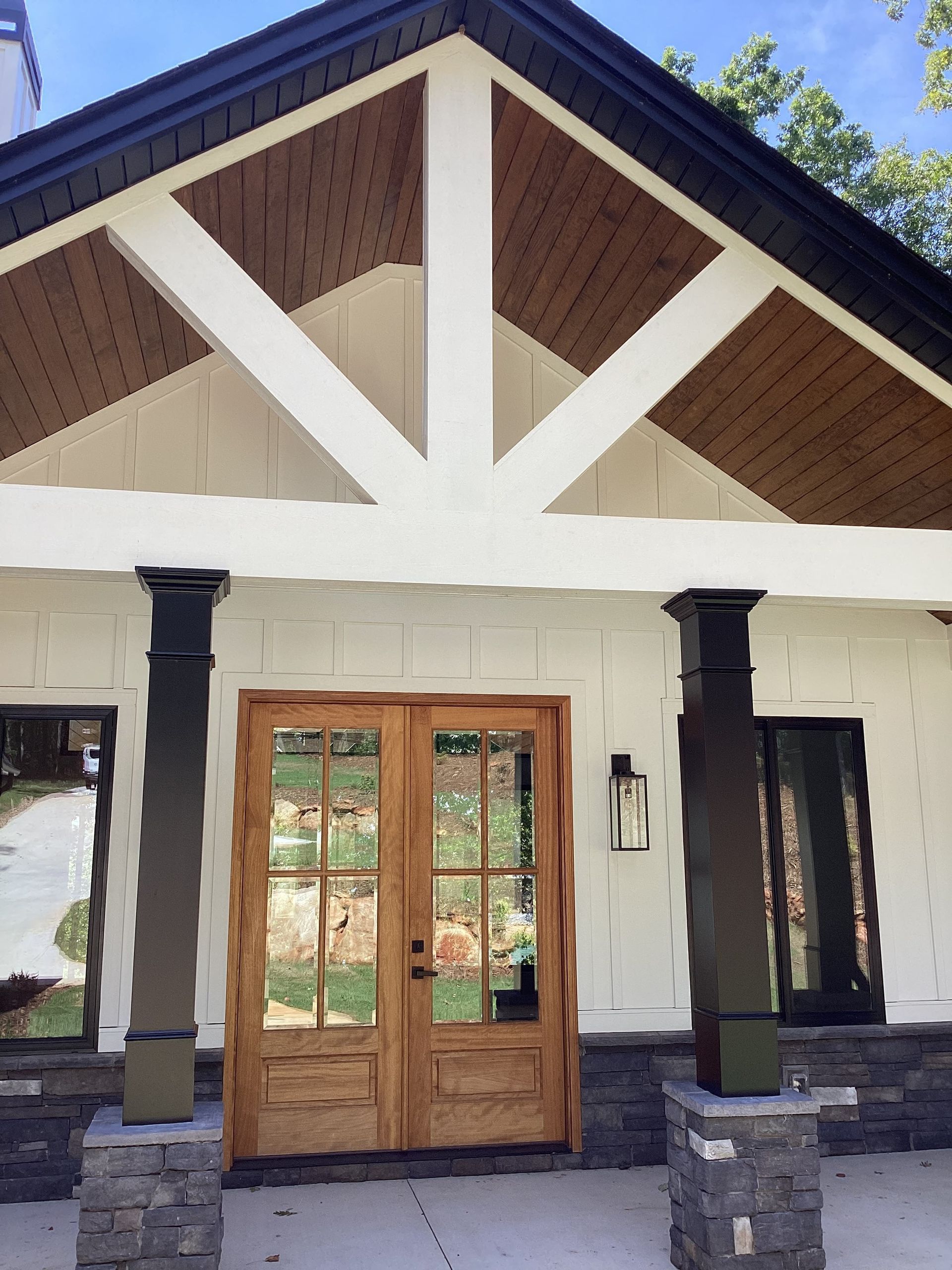 A white house with a wooden door and a black roof.