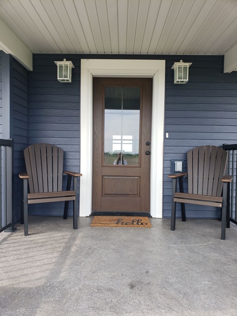 A porch with two chairs and a welcome mat