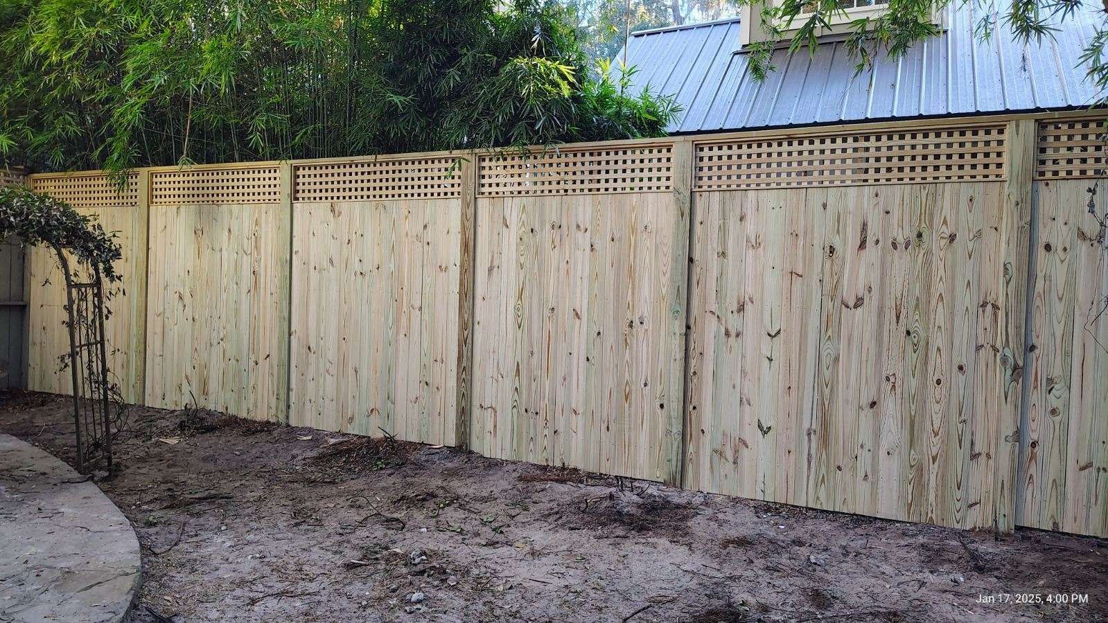 A wooden fence is in the backyard of a house.