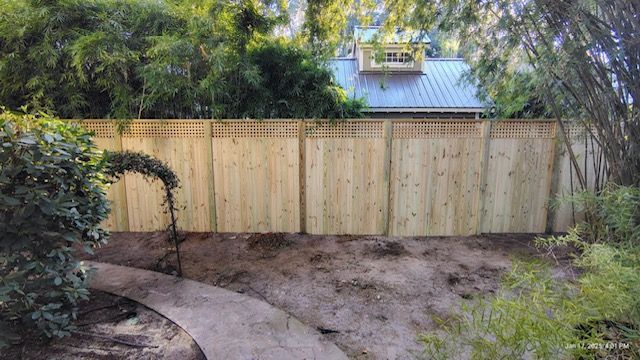 A wooden fence surrounds a dirt path in a backyard.
