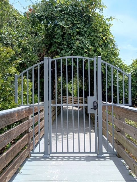 A metal gate leading to a wooden bridge