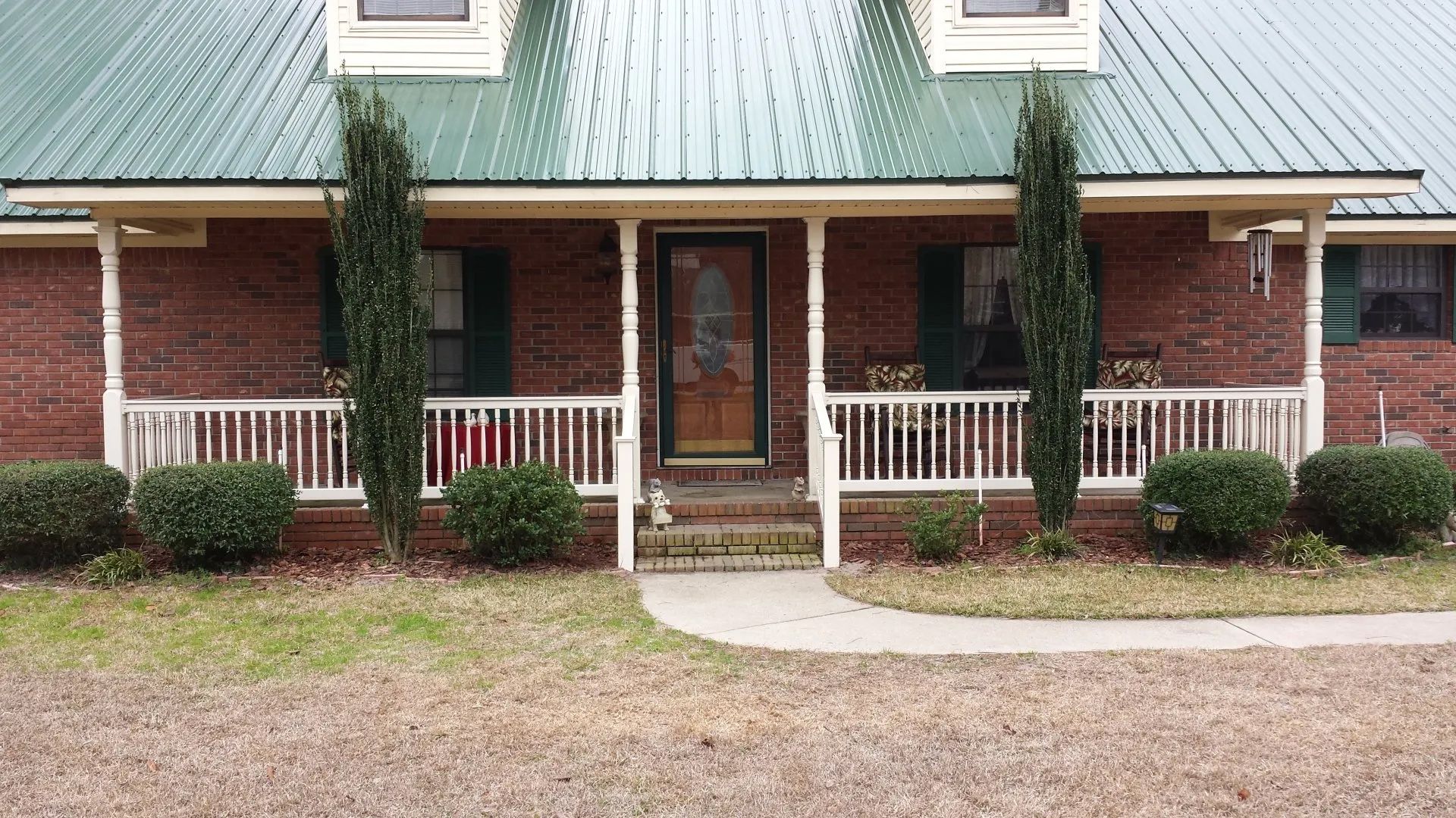 a brick house with a green roof and a porch