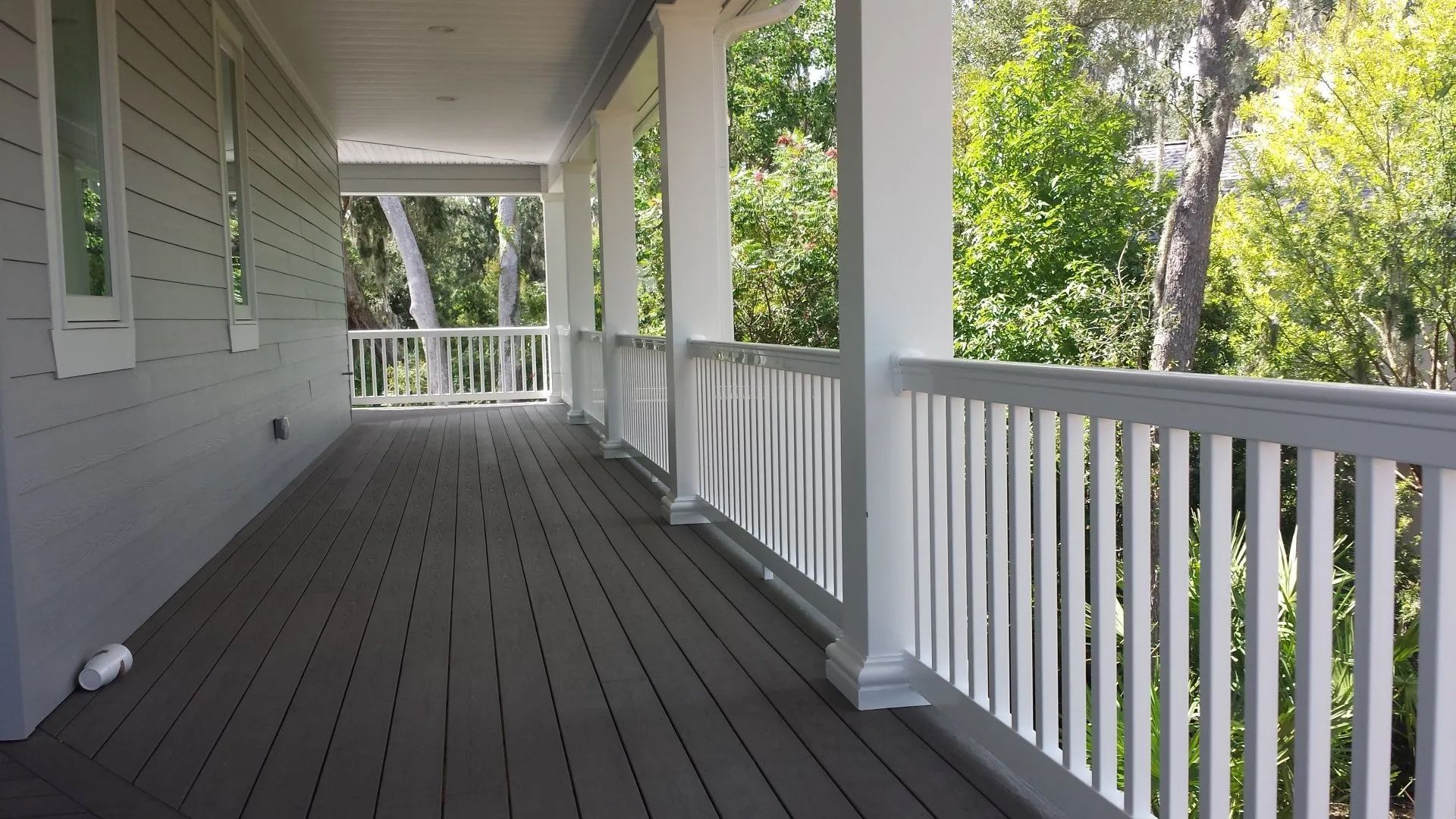 a porch with a gray deck and white railing