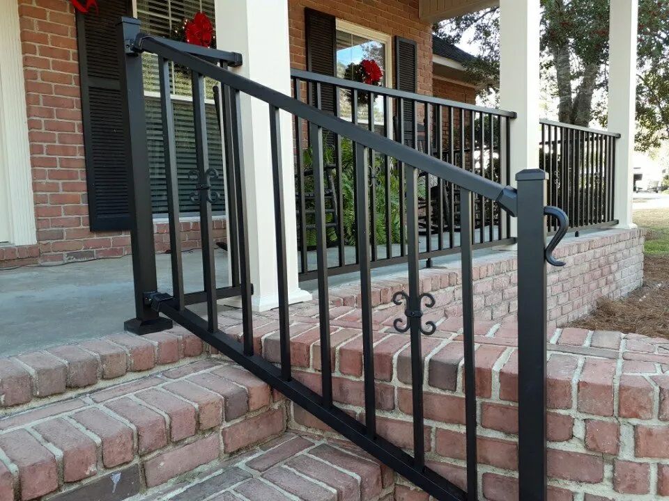 there is a black railing on the porch of a brick house