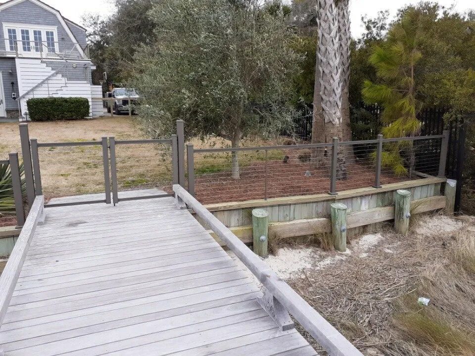 a wooden walkway leading to a house with a car parked in front of it