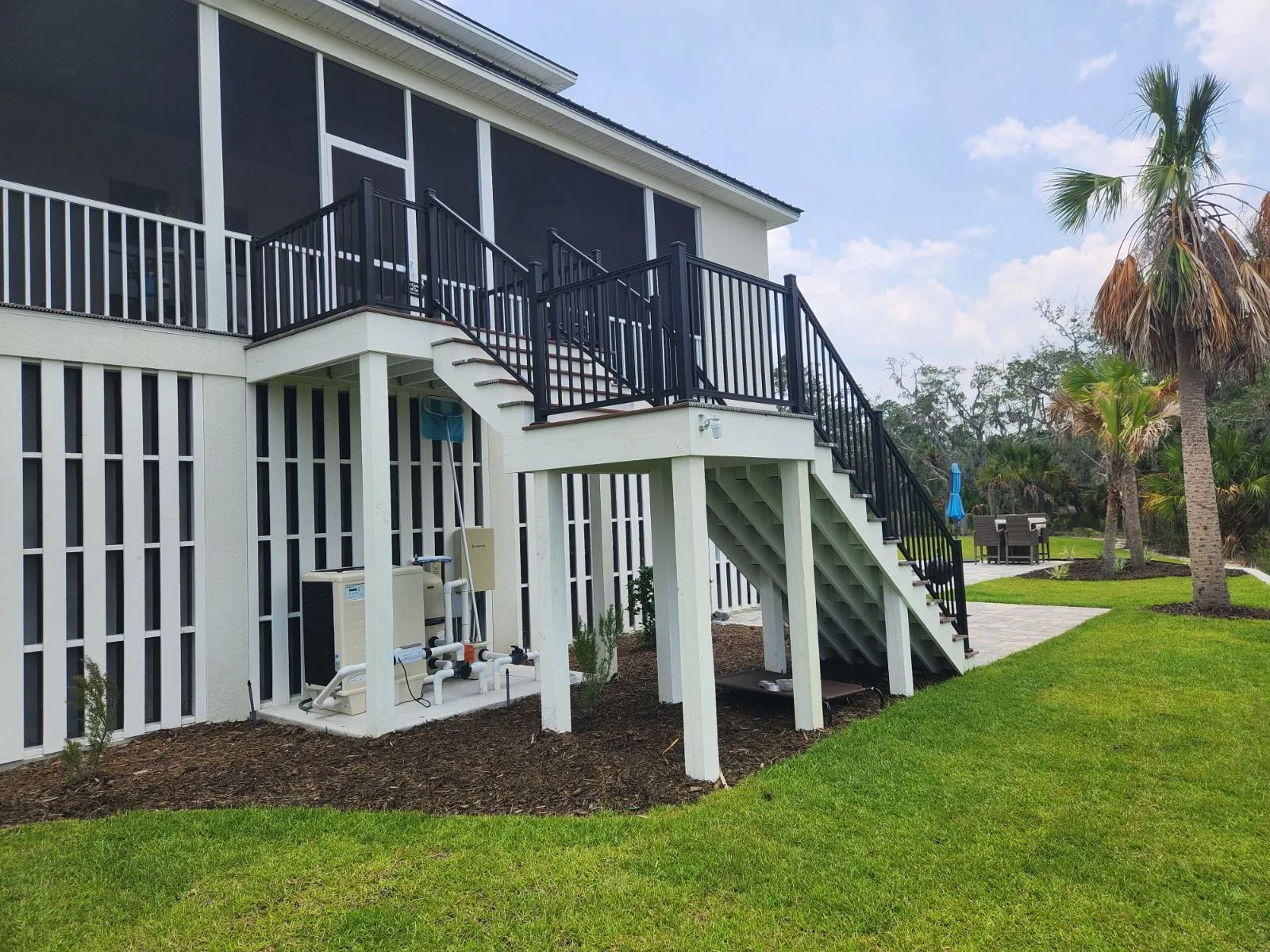 a white house with a screened-in porch and stairs leading up to it