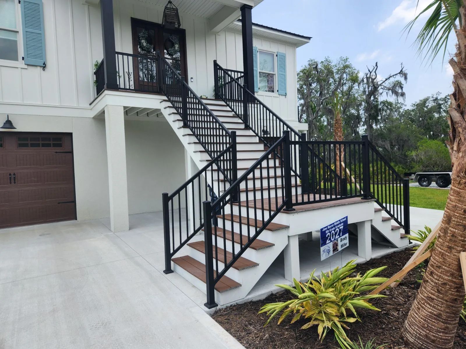 a white house with a black railing and stairs