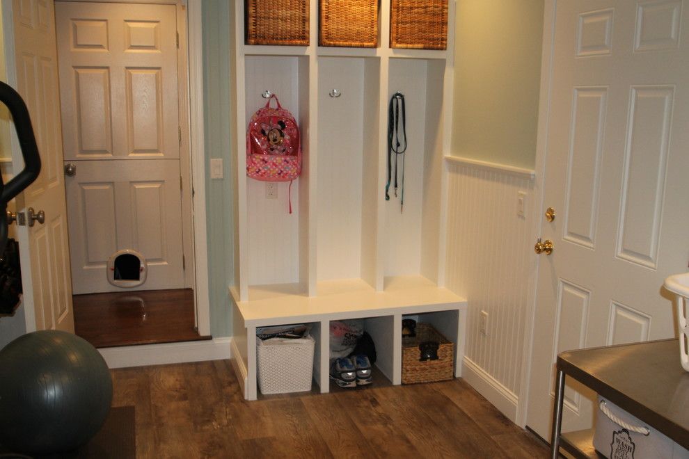 A room with a cat door , a bench , baskets , and a exercise ball.