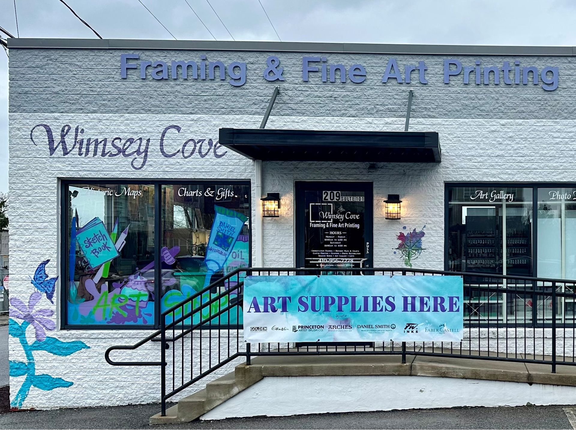 Storefront with “Framing & Fine Art Printing” sign and “Art Supplies Here” banner over the entrance