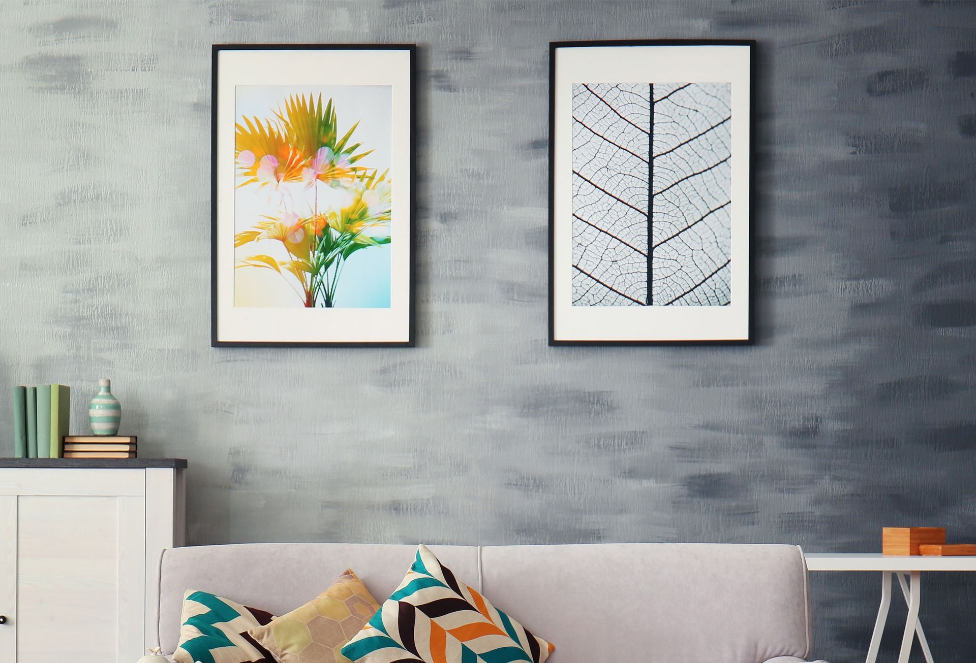 Framed floral and leaf prints above a gray sofa in a modern living room