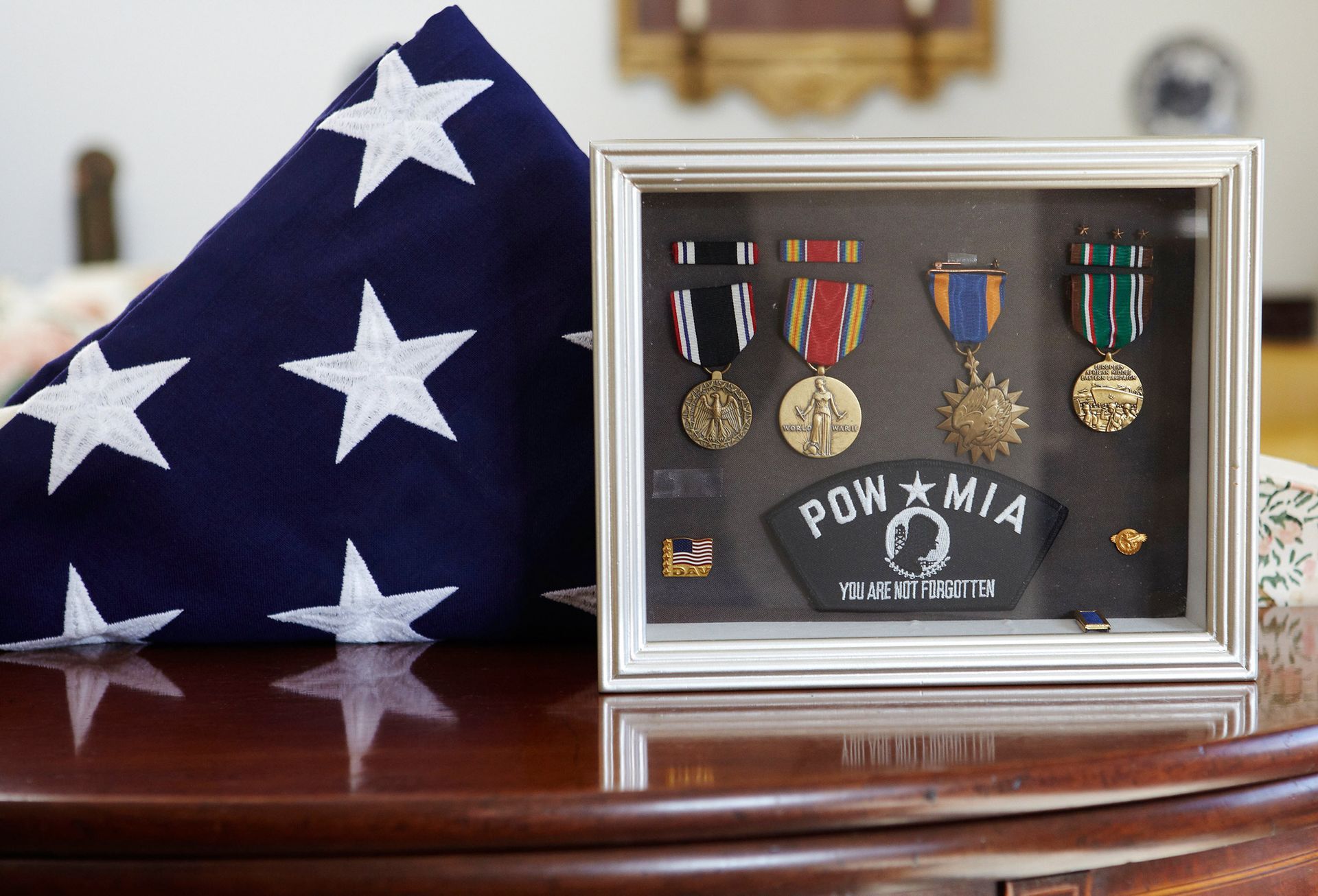 Folded U.S. flag beside framed military medals on a wooden table