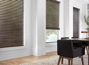 A dining room with a table and chairs and blinds on the windows.