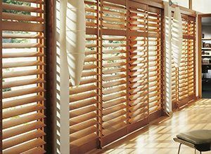 A room with wooden shutters on the windows and a chair.