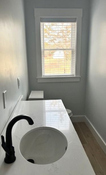 A bathroom with a sink , toilet and window.