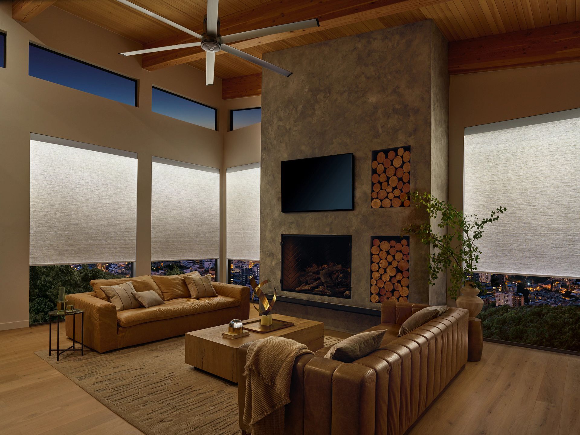 A living room with a couch , fireplace , television and ceiling fan.