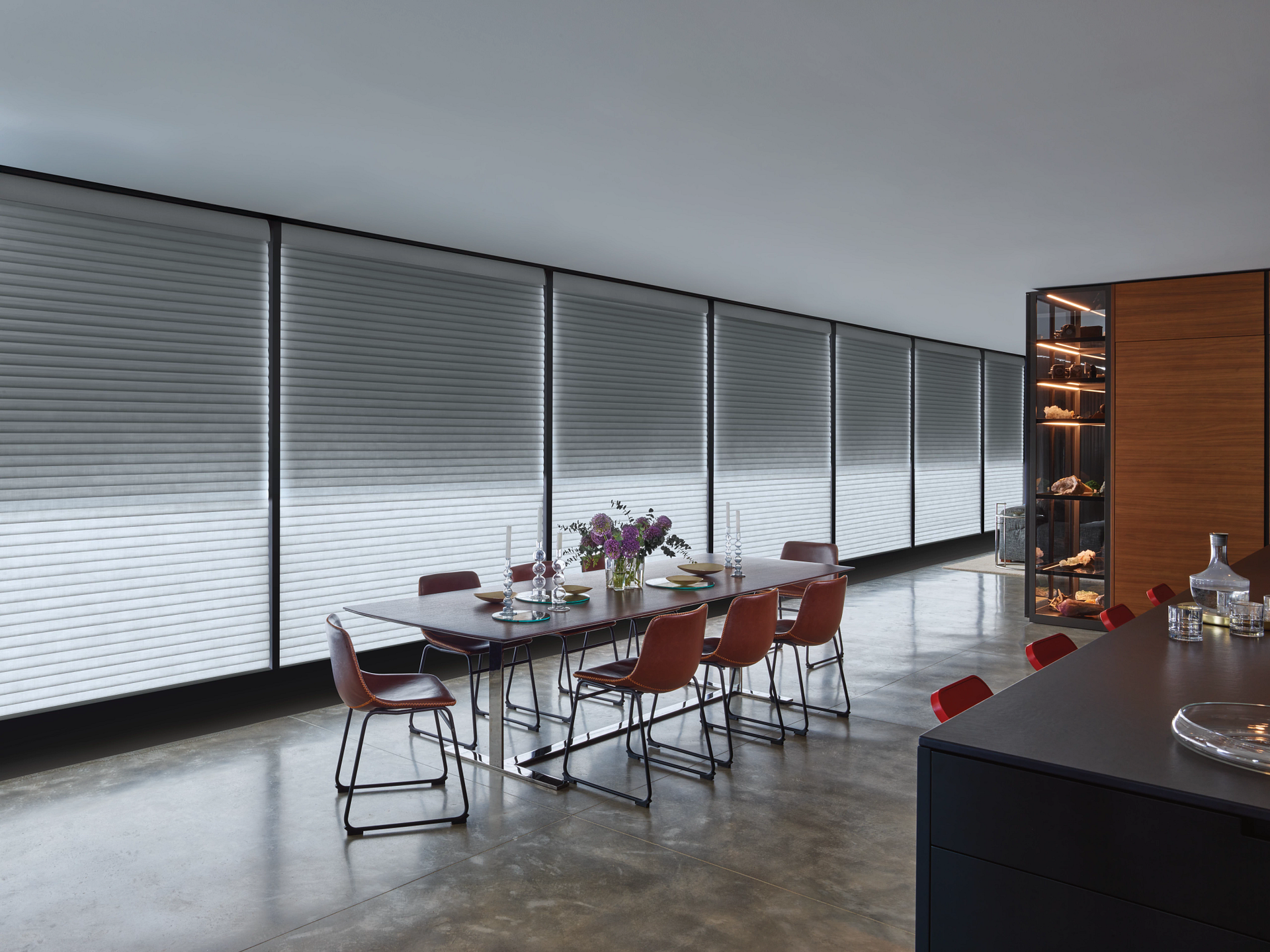 A dining room with a table and chairs in front of a large window.