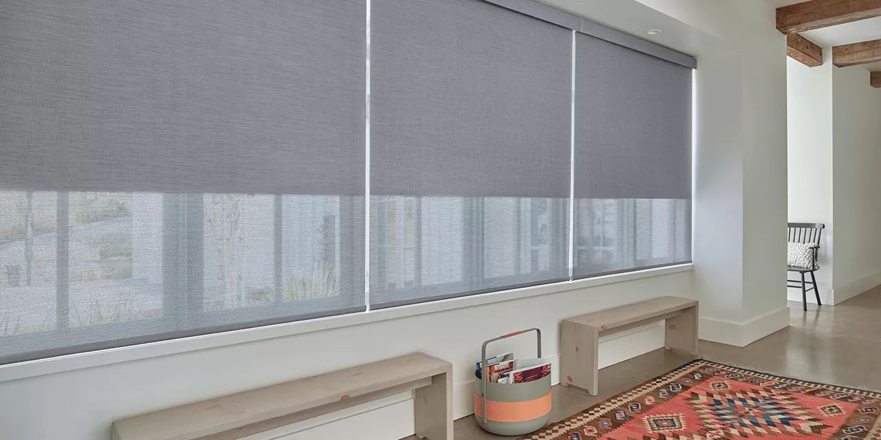 A living room with a rug and blinds on the windows.