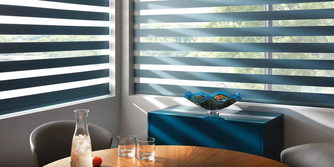 A dining room with a table and chairs and a window with striped blinds.