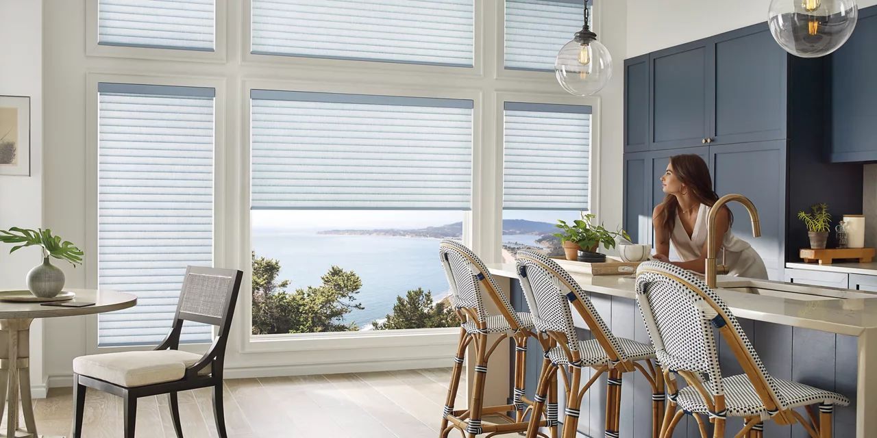 A woman is sitting at a kitchen counter looking out the window.