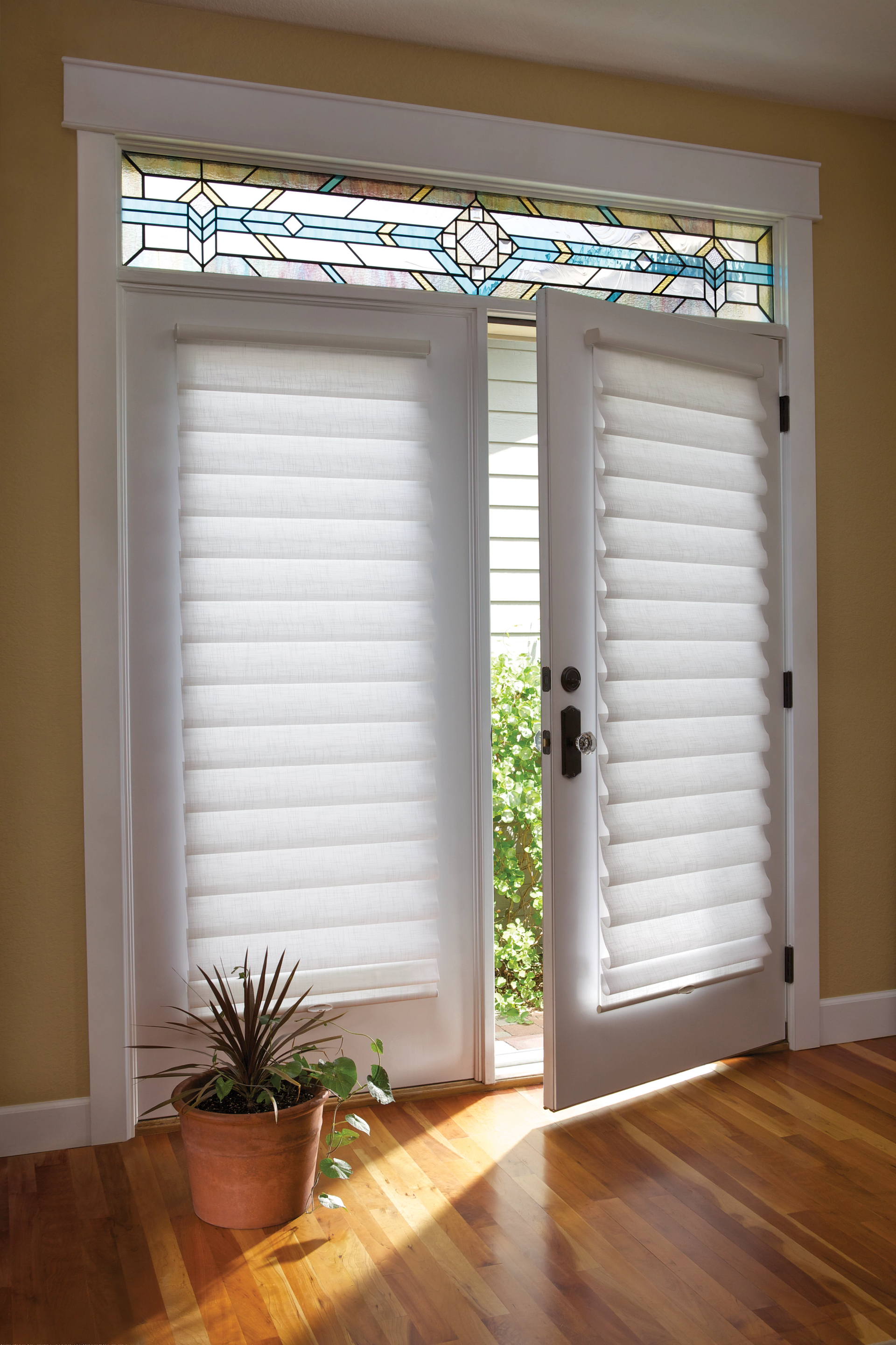 A door with white blinds and a potted plant in front of it.