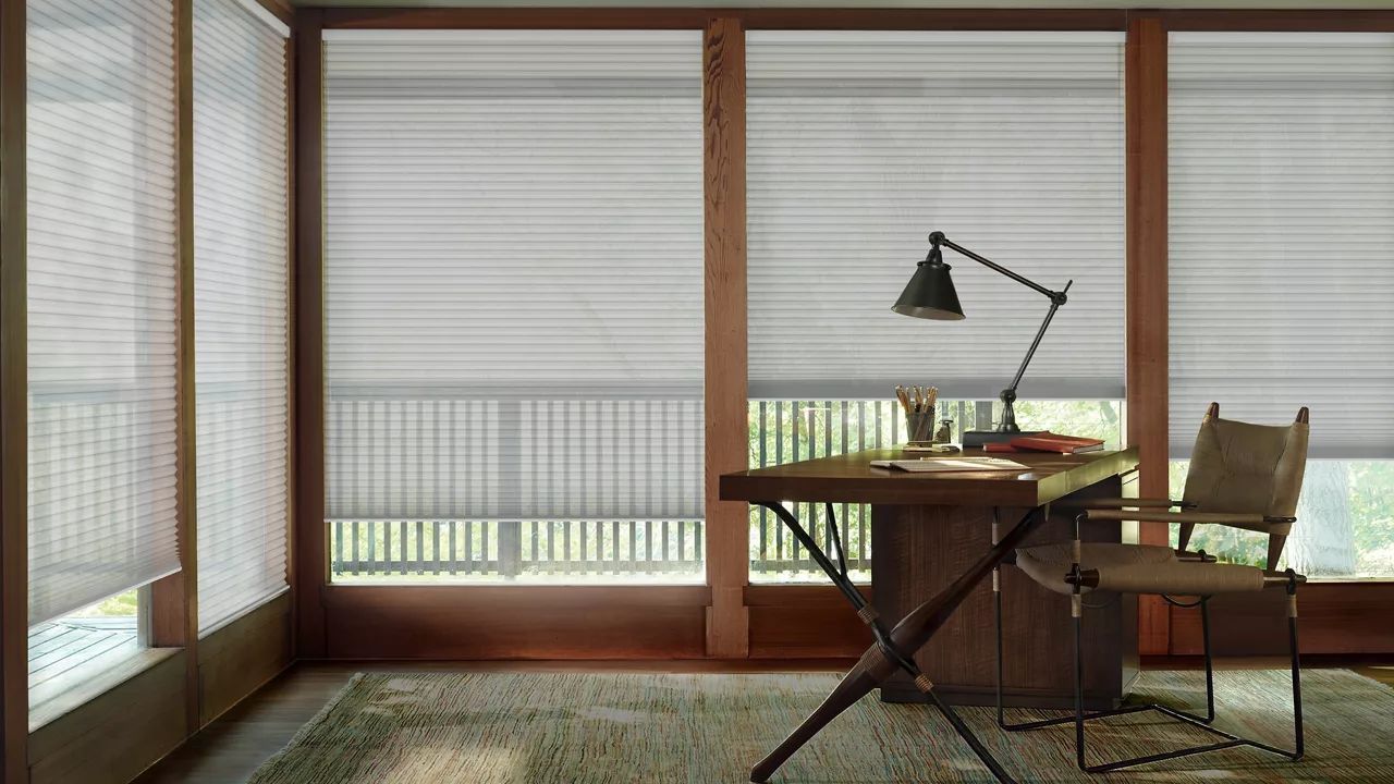 A room with a desk, chair, lamp, and sliding glass doors.