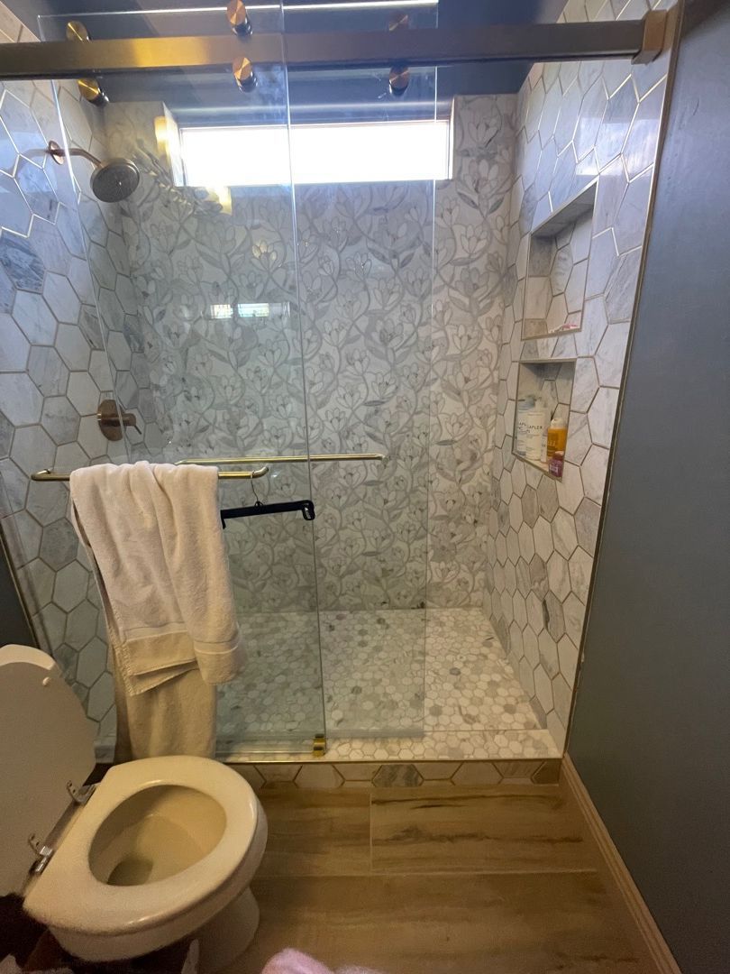 A bathroom with a toilet and a walk in shower.