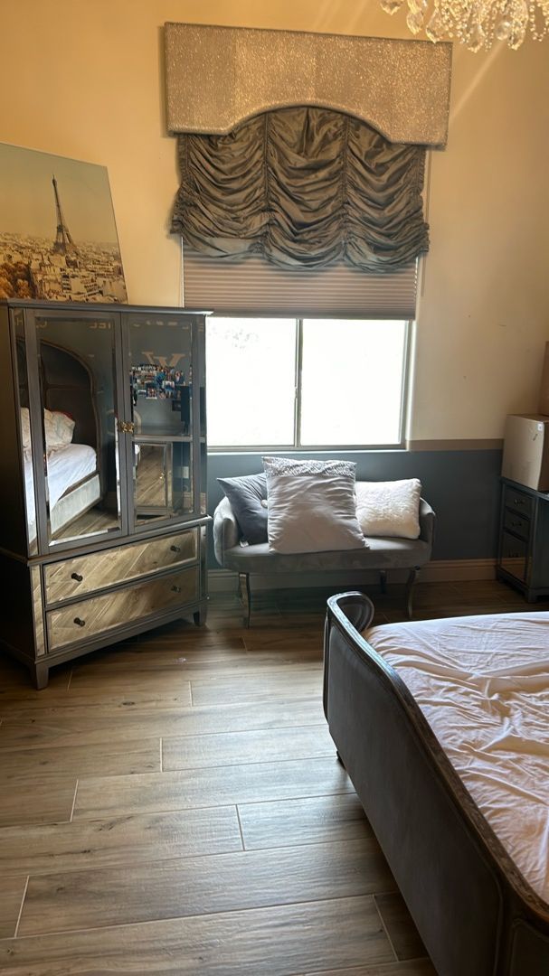 A bedroom with a bed , dresser , couch and window.