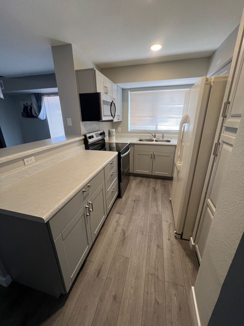 A kitchen with white cabinets , stainless steel appliances , and hardwood floors.
