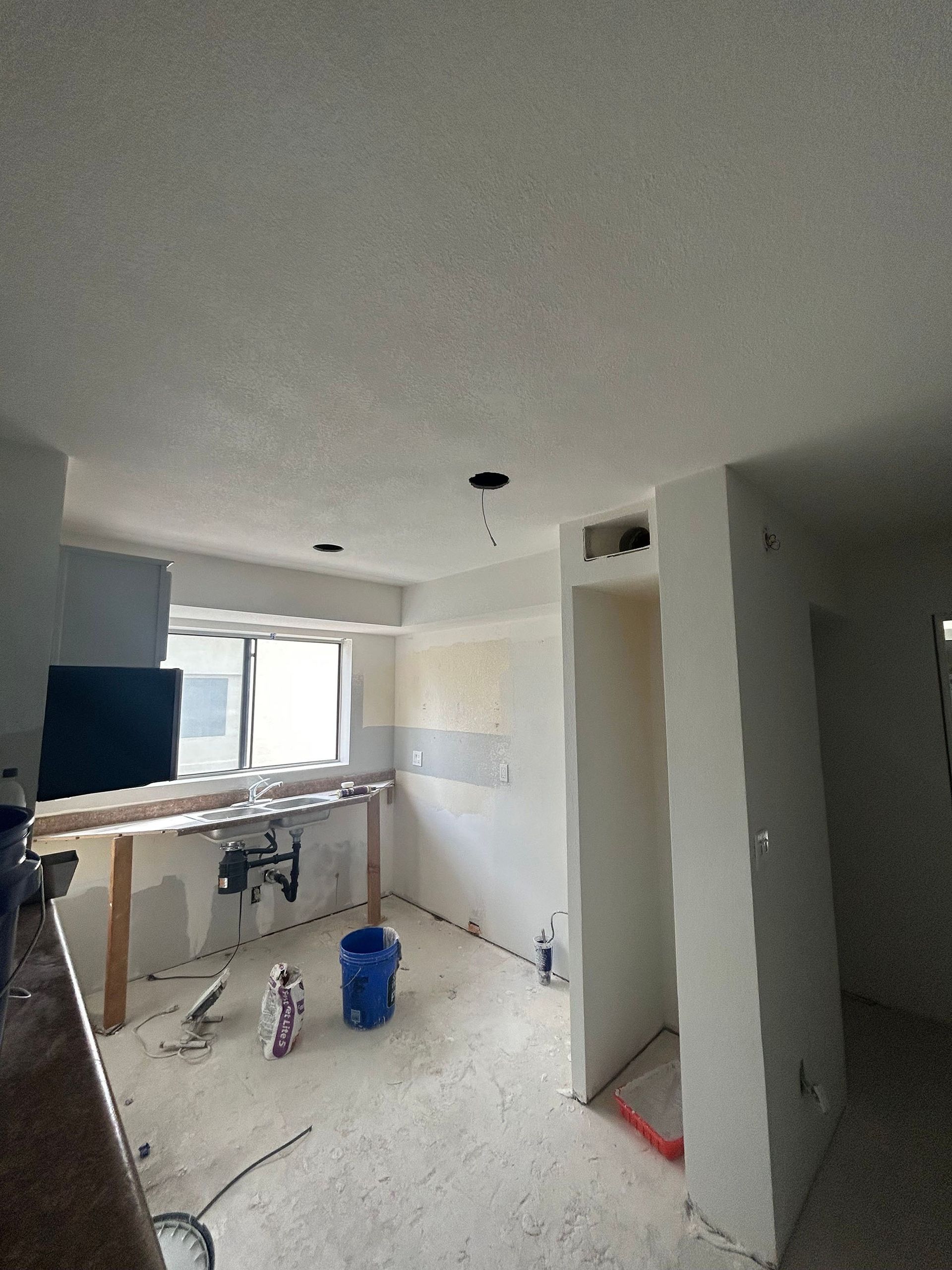 A kitchen under construction with a blue bucket on the floor.