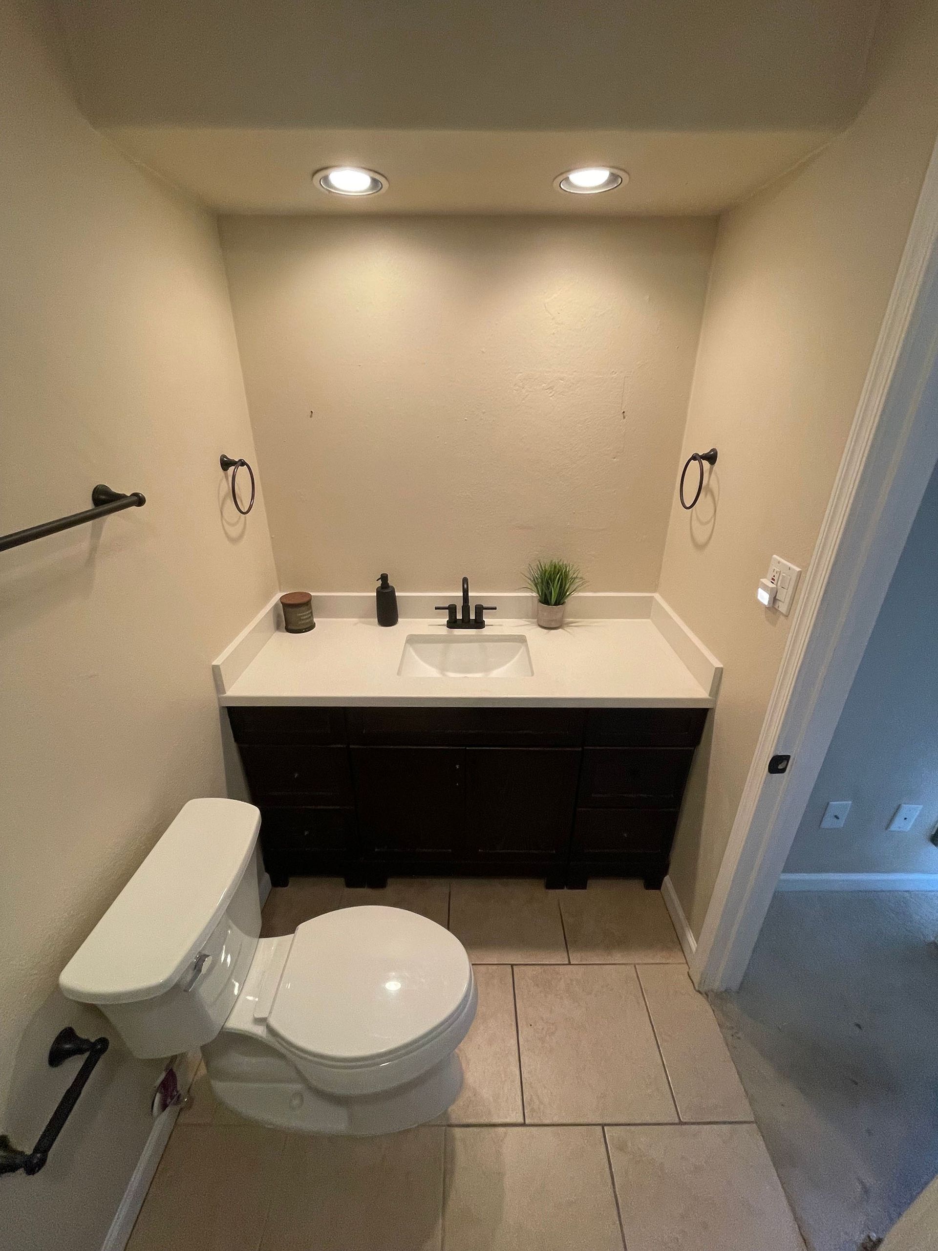 A bathroom with a toilet , sink and vanity.