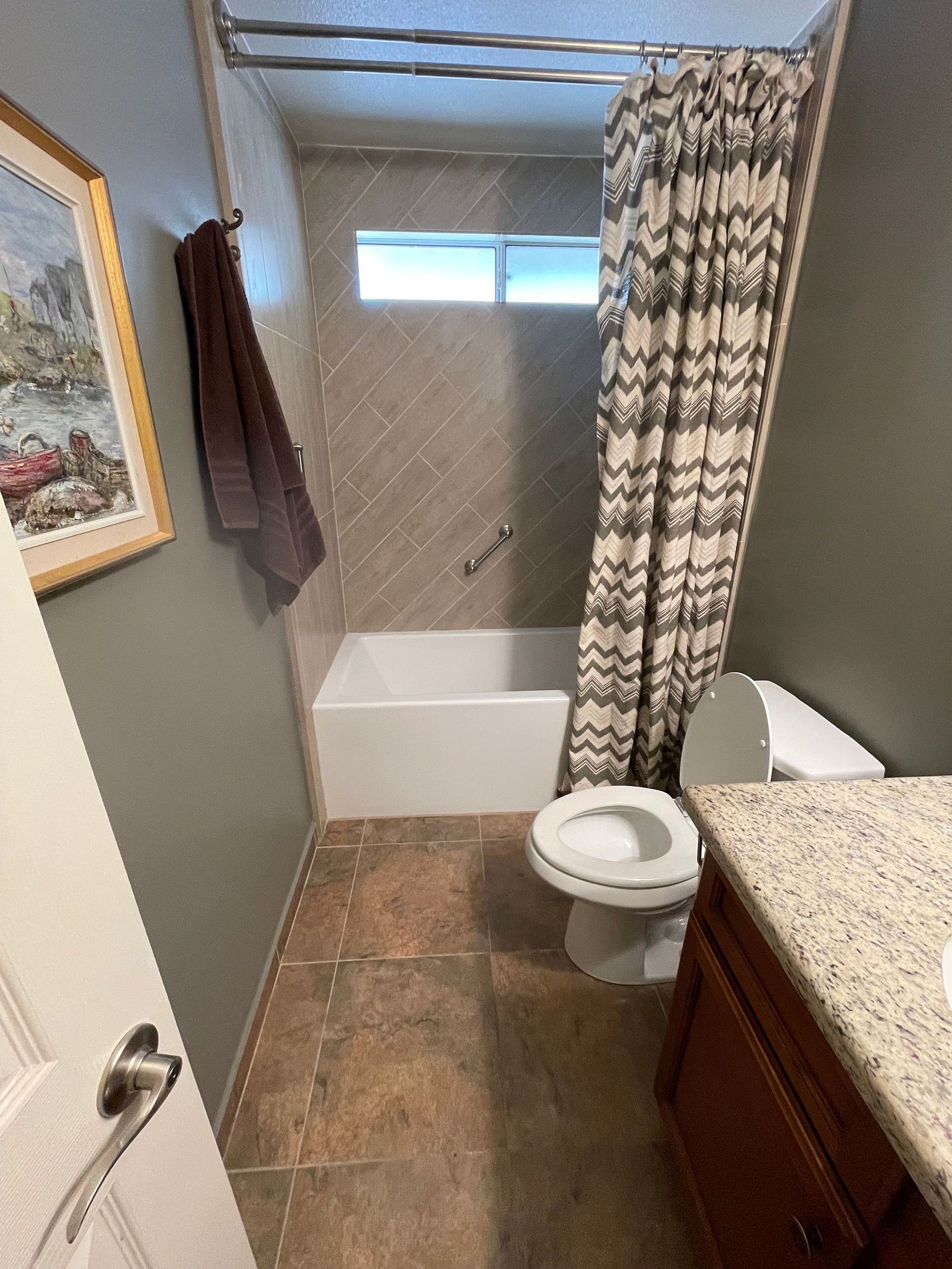 A bathroom with a toilet , bathtub and shower curtain.