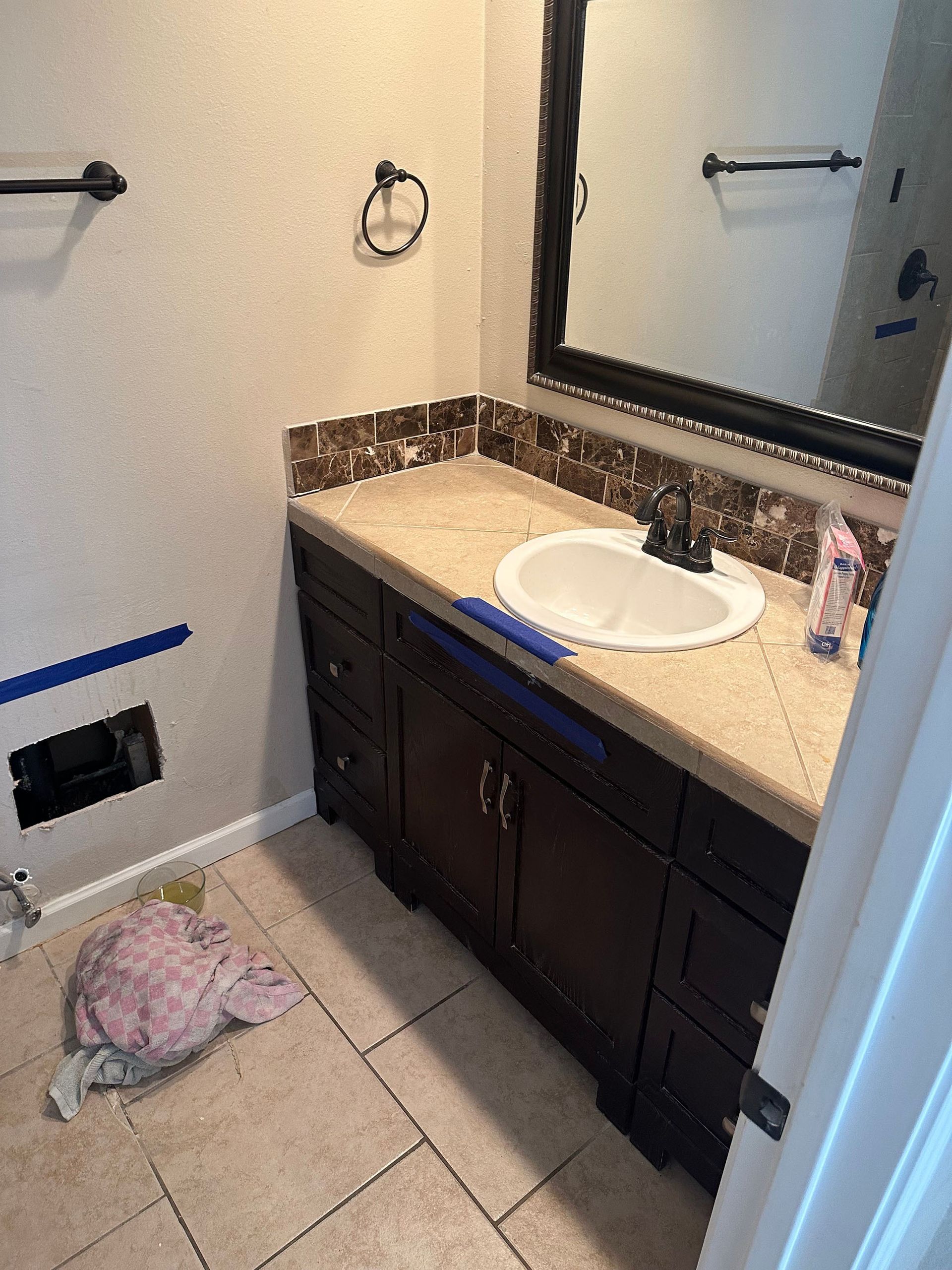 A bathroom with a sink , mirror and towel rack.