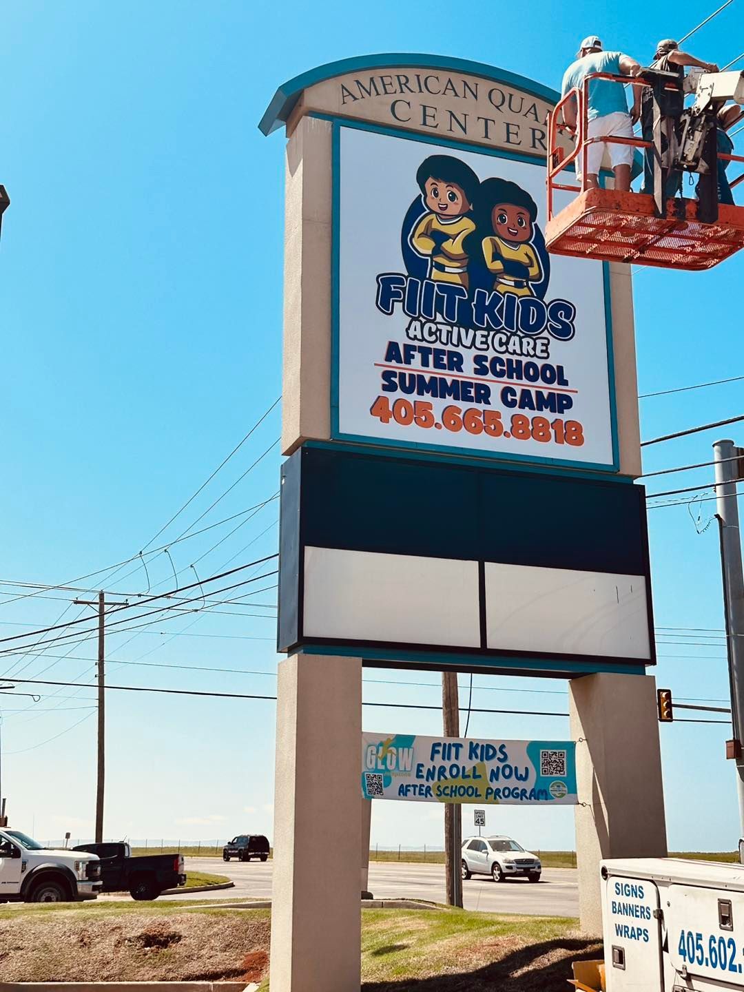 A large billboard is being painted by two men on a scaffolding.