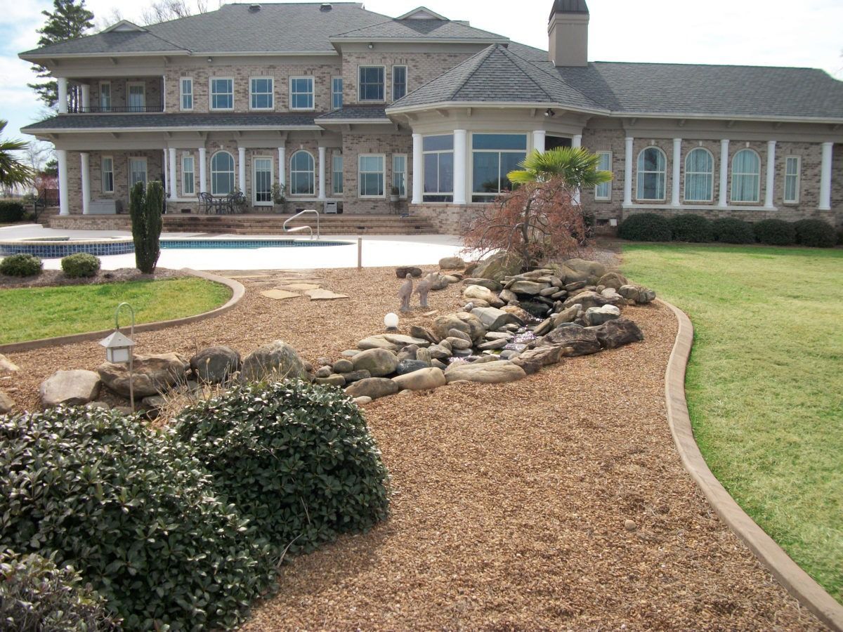 Large two-story house with landscaped front yard, rock garden, and curving mulch path