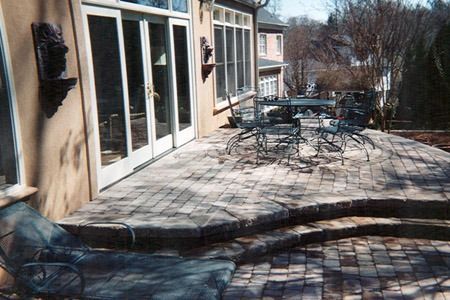 Patio with tables and chairs outside a building, with a low curved brick wall in the foreground