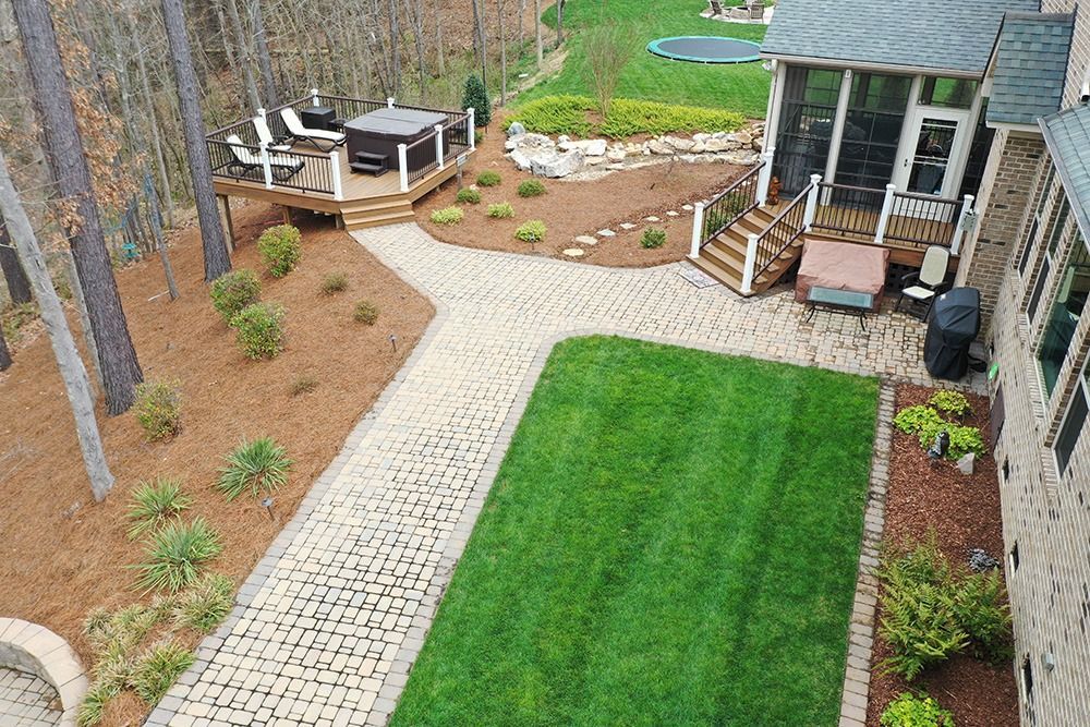 Backyard with green lawn, stone path, patio seating, and a small shed beside a wooded fence