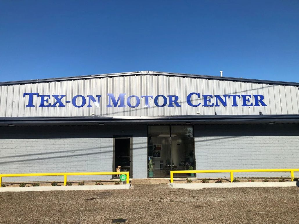 Tex-On Motor Center storefront with blue sign and yellow safety rails under a clear sky