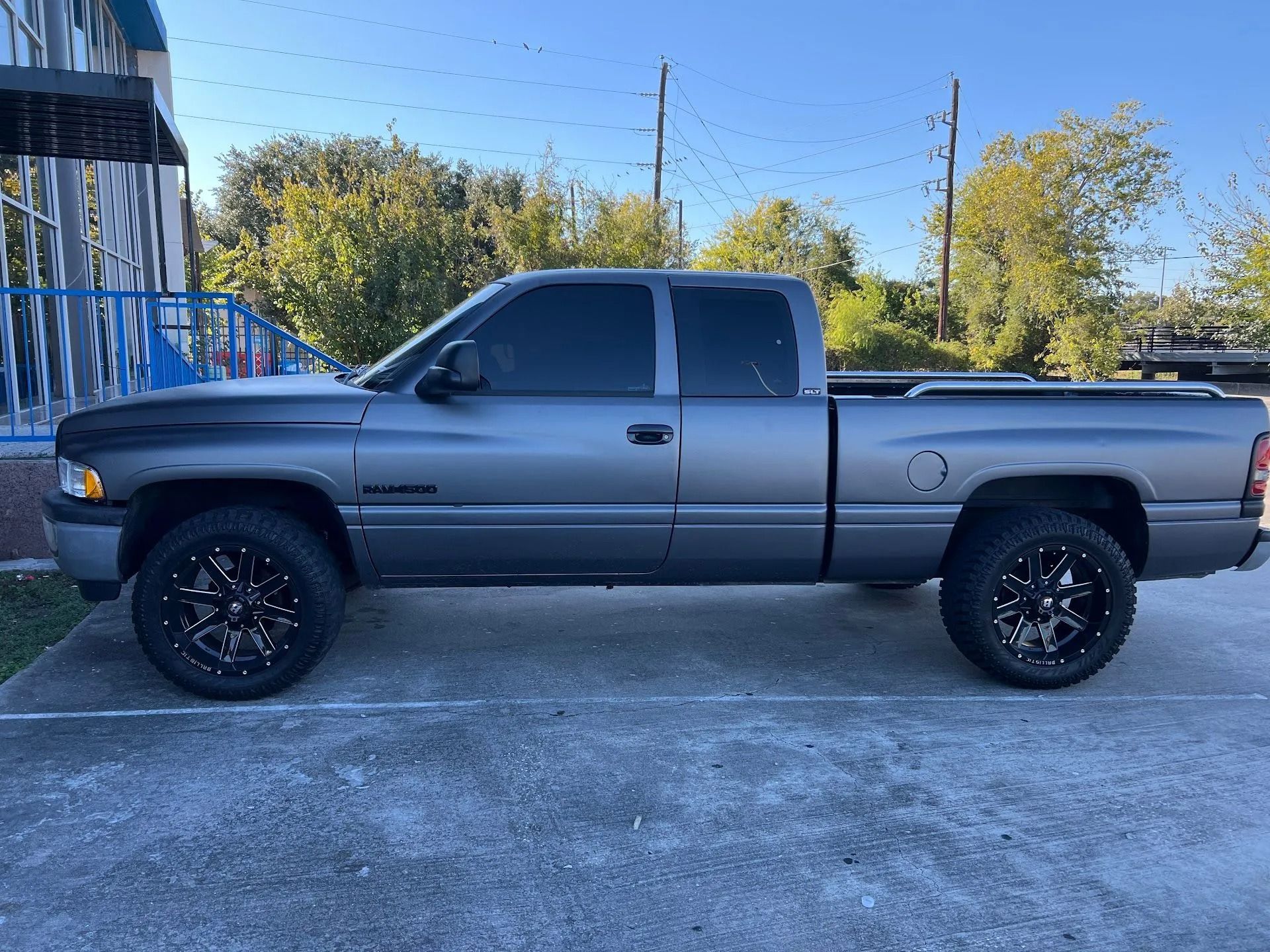 Gray pickup truck parked on a driveway beside a blue house under a clear sky