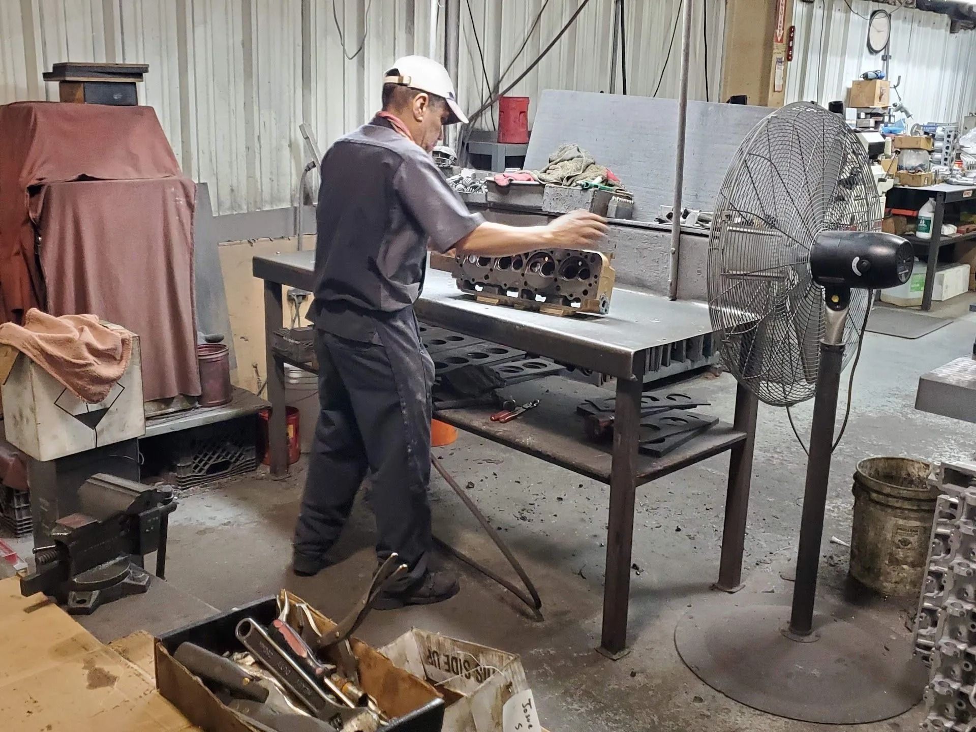 Worker assembling parts at a metal workbench in an industrial workshop
