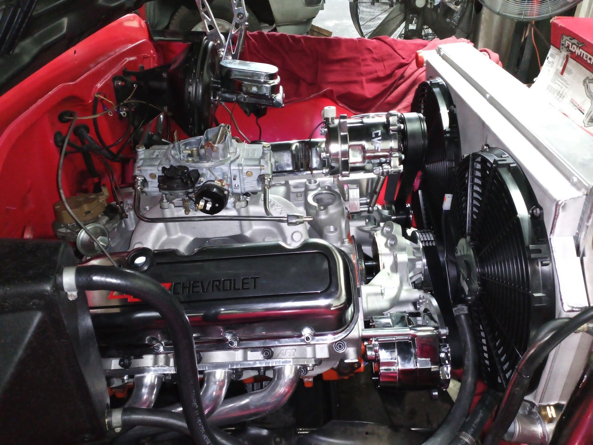 Car engine bay with a polished V8 engine, red bodywork, and exposed mechanical components