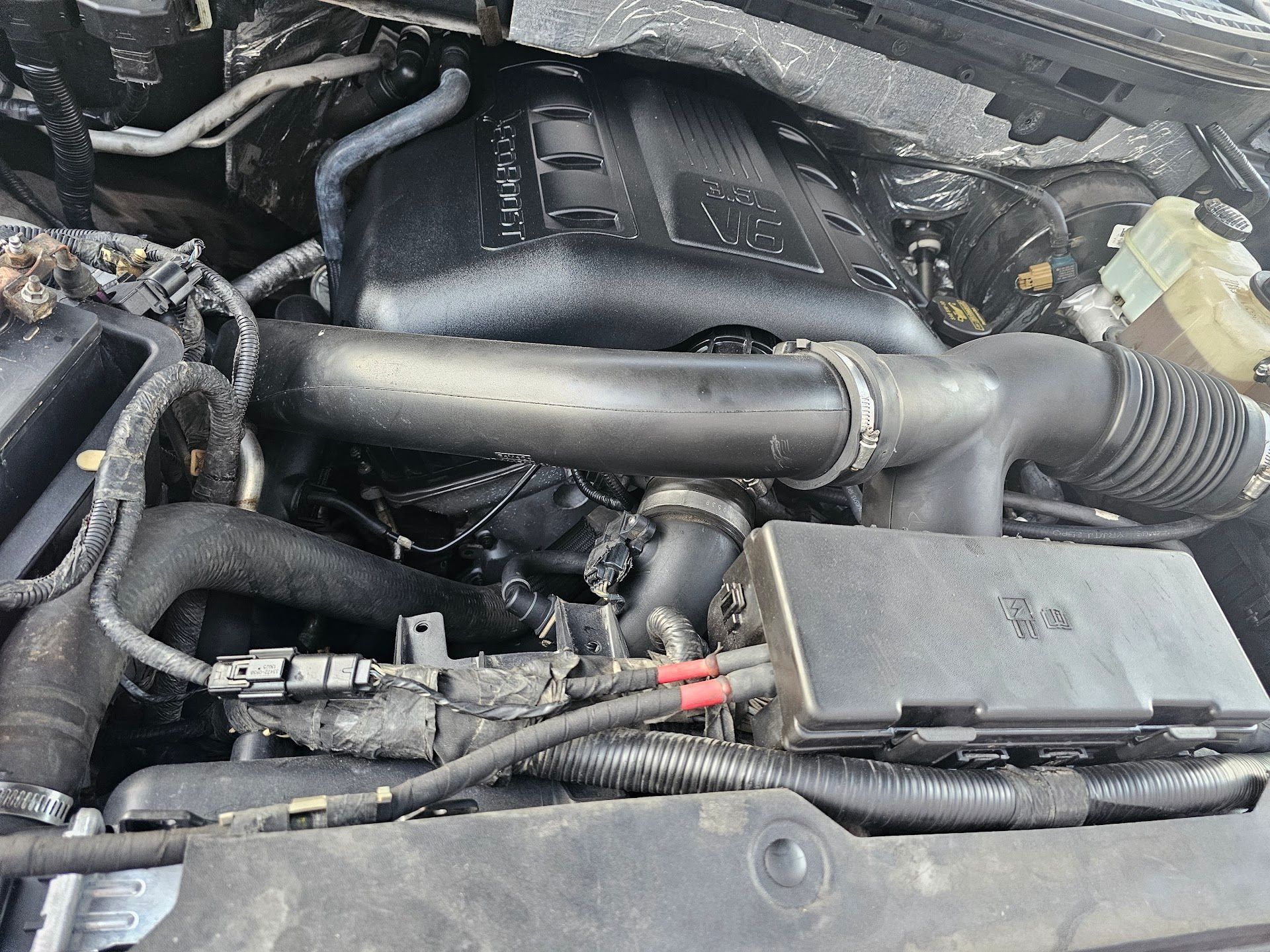 Close-up of a car engine bay with black air intake tubing and wiring.
