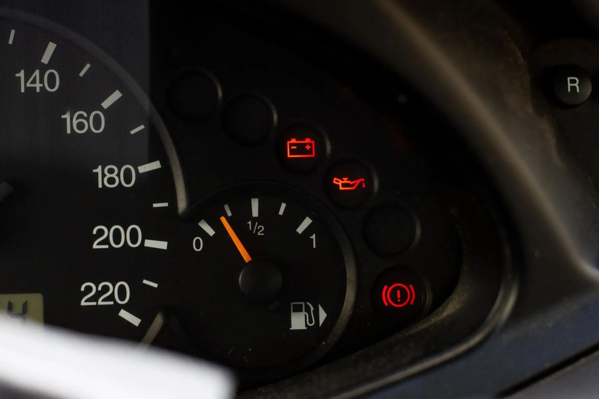 Car dashboard with speedometer and red warning lights illuminated