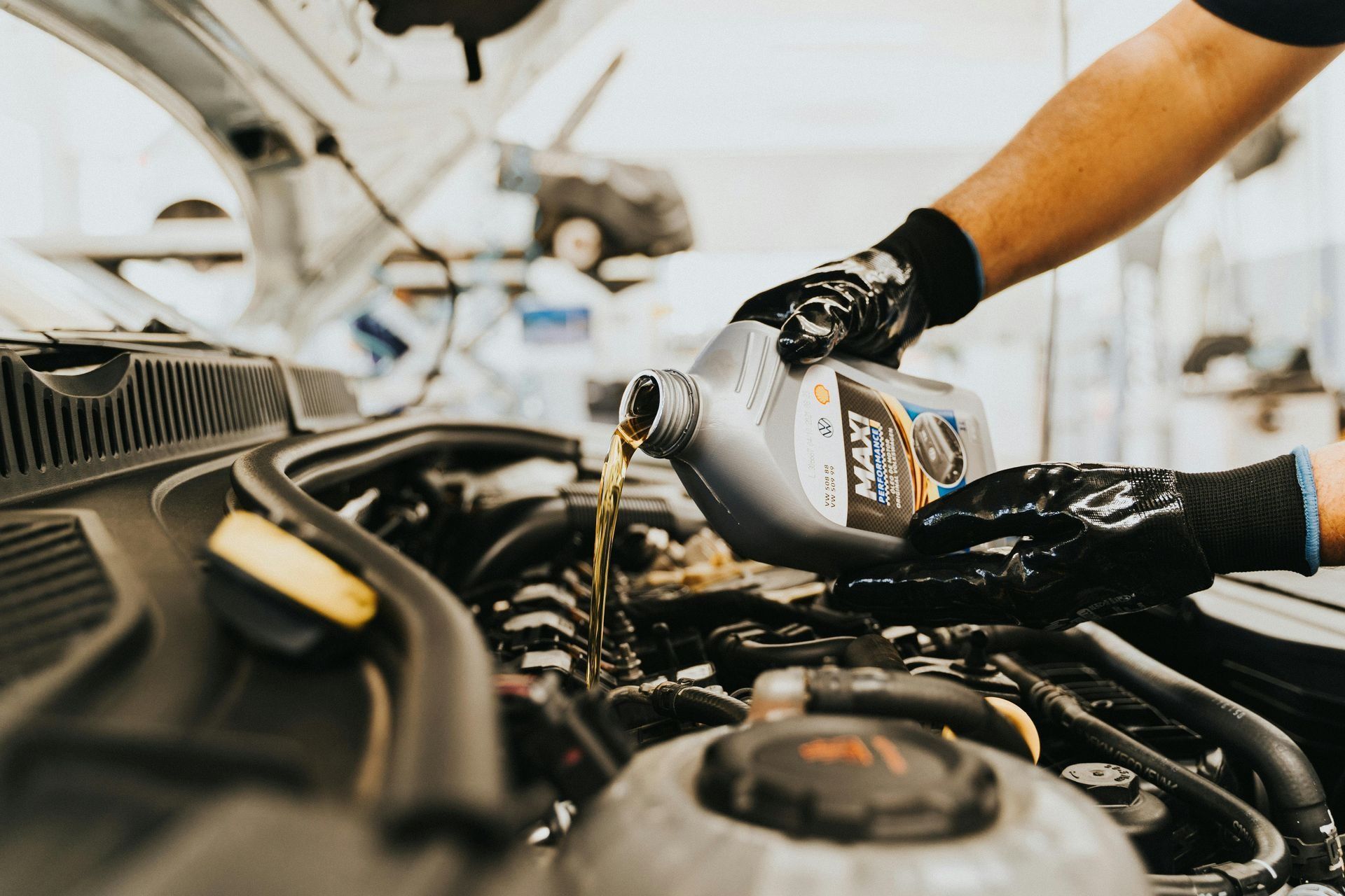 Mechanic pouring engine oil into a car engine in a garage