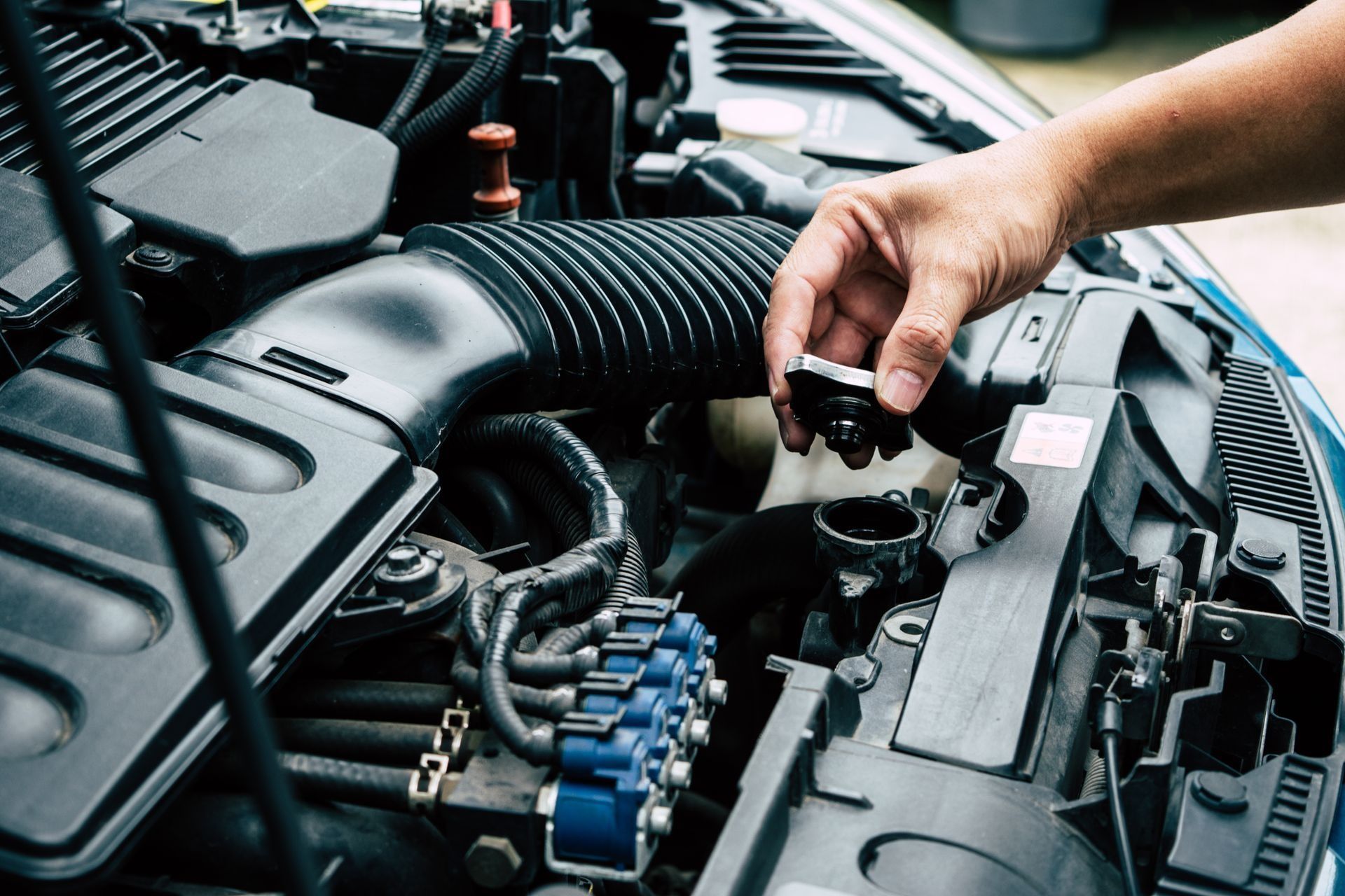Hand adding oil to a car engine compartment with the hood open