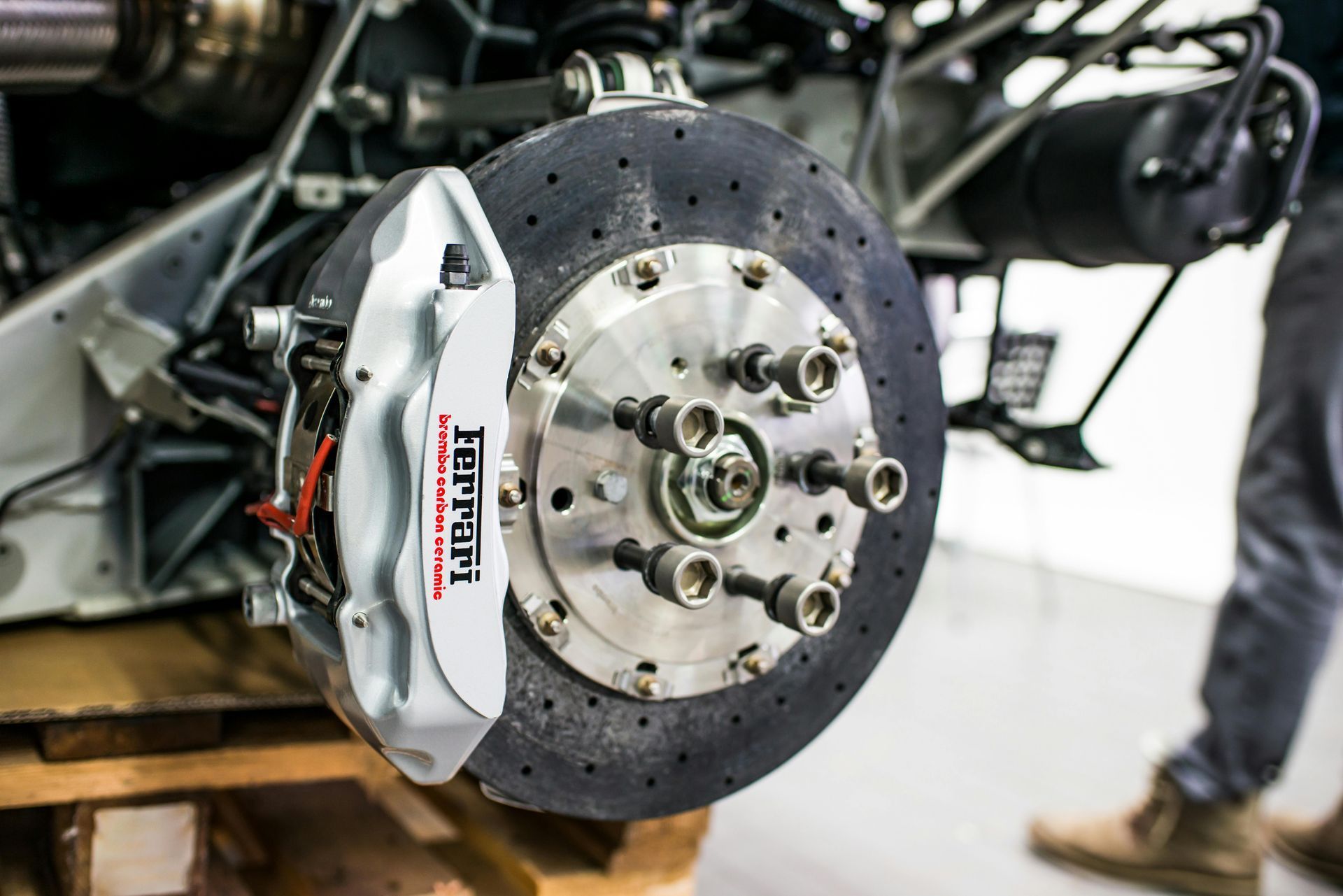 Close-up of a car brake rotor and silver caliper on a vehicle chassis.